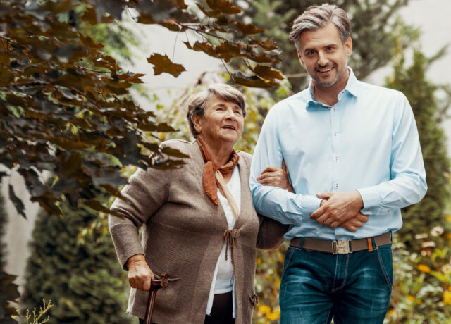 Man and elderly woman walking in garden