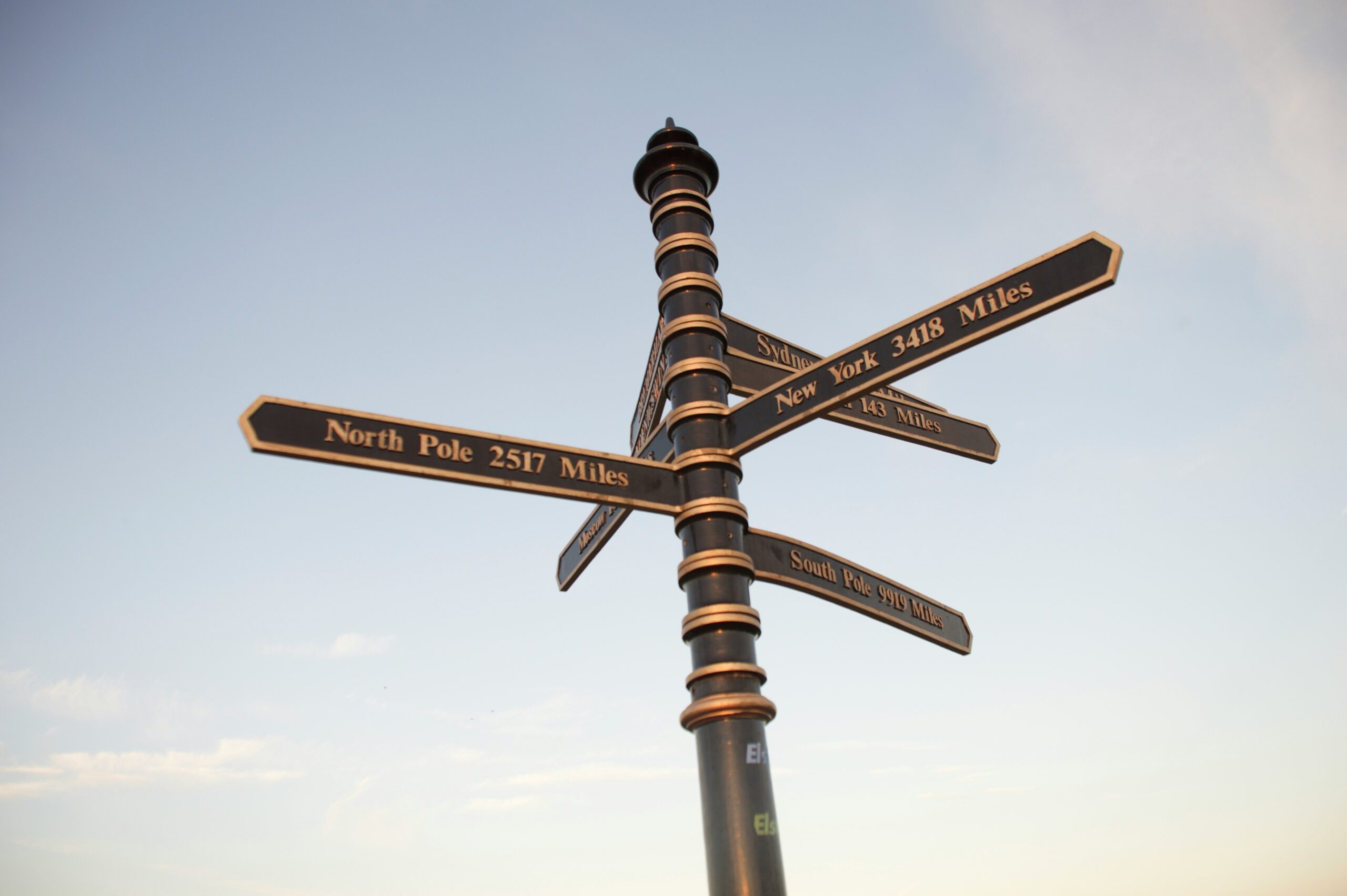 Signpost in Humberston pointing to various global destinations, including the North Pole (2517 miles), New York (3418 miles), and South Pole (9919 miles), against a clear sky.