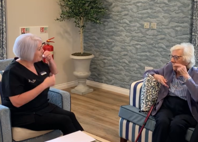 Resident learning Makaton sign language with a team member at Humberston House Care Home.